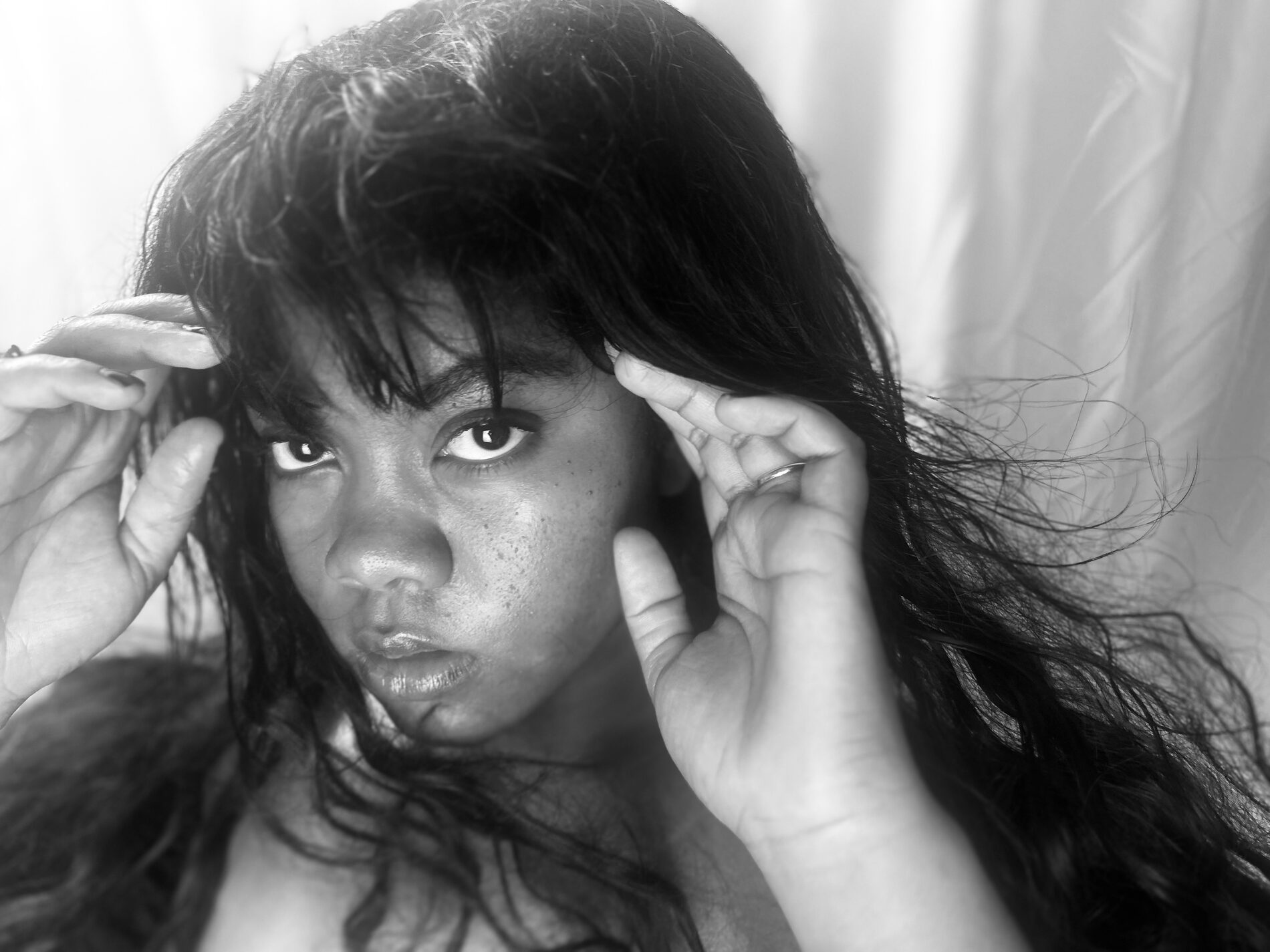 Gros plan de Rosa Zand, les mains dans les cheveux, regard intense, photo noir et blanc
